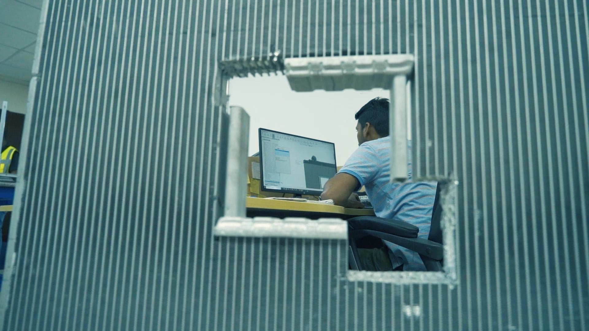 Automoty engineer at workstation, framed by a heat-exchanger core