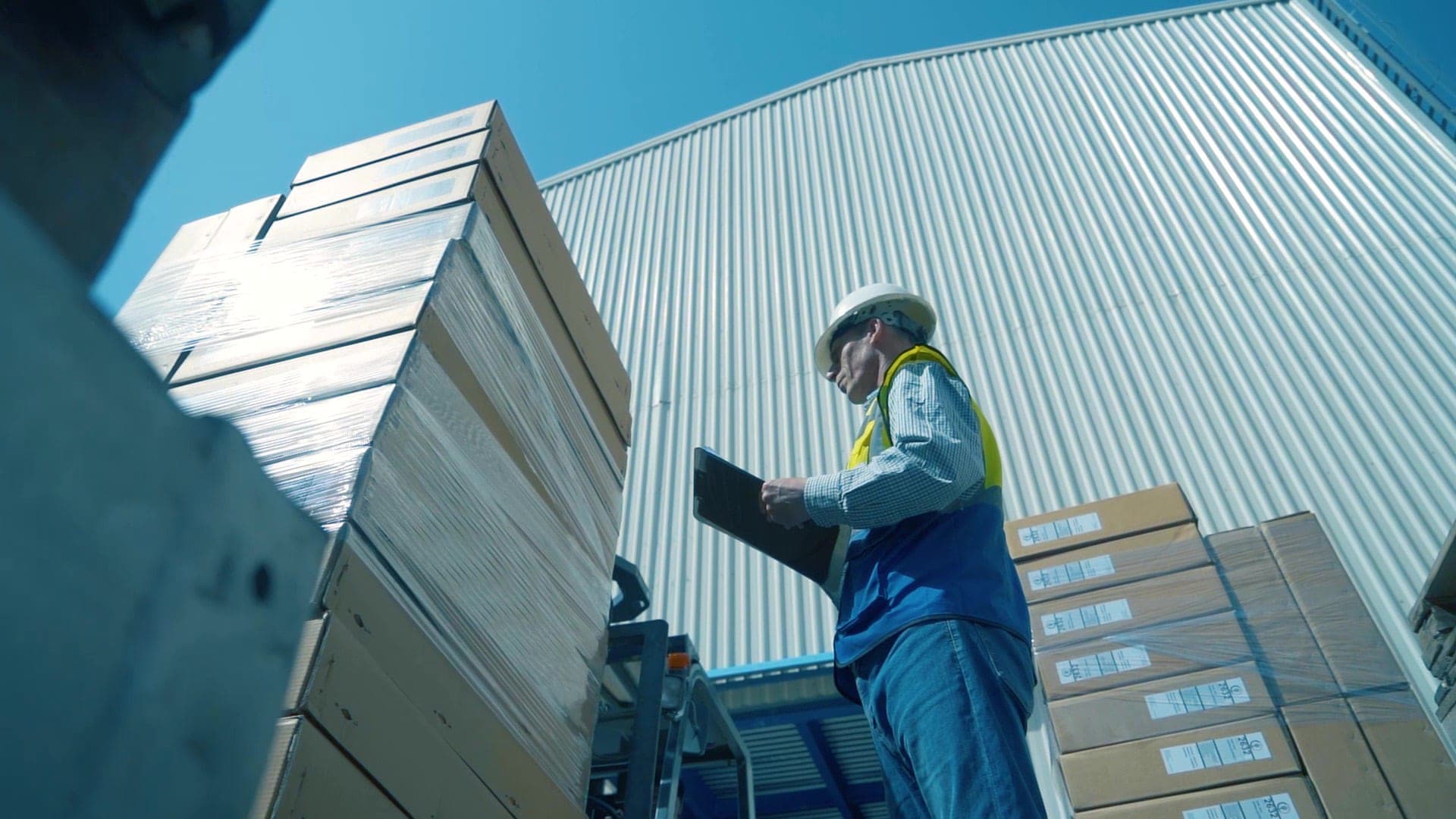 Automoty operator with tablet beside palletized outbound shipments
